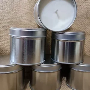 four tins of candles with a white candle in each